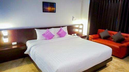 a bedroom with a large bed and a red chair at Aziss Boutique Hotel - SHA Plus in Phitsanulok