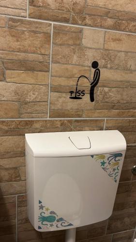 a toilet in a bathroom with a sign on the wall at Toscan Panzió in Gyál
