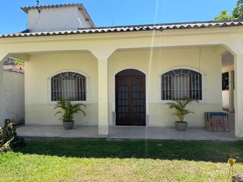 a house with two potted plants in front of it at Casa em São Pedro da Aldeia - RJ in São Pedro da Aldeia