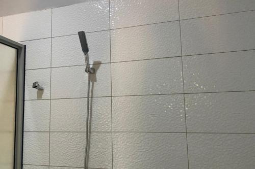 a white tiled wall in a bathroom with a shower at Lovely 4Bedroom Home in Akright - Tara Residence Akright in Buzzi
