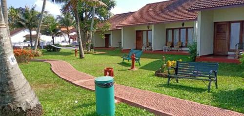 a park with benches and a house with a hammock at Abad Whispering Palms in Kumarakom