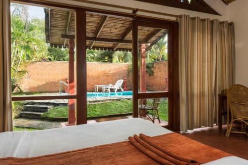 a bedroom with a bed and a view of a pool at Abad Whispering Palms in Kumarakom