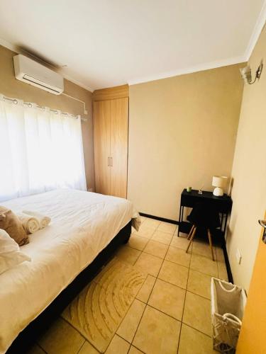 sypialnia z łóżkiem i biurkiem z oknem w obiekcie R&R Stays w mieście Gaborone