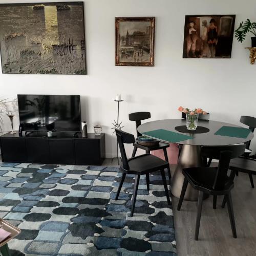 - un salon avec une table, des chaises et une télévision dans l'établissement Appartement familial à L’Île-Saint-Denis, 67 m², balcon privé, à LʼÎle-Saint-Denis