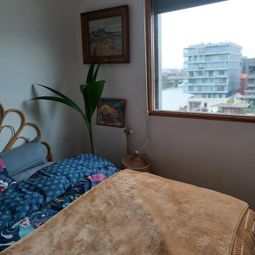 une chambre avec un lit et une grande fenêtre dans l'établissement Appartement familial à L’Île-Saint-Denis, 67 m², balcon privé, à LʼÎle-Saint-Denis