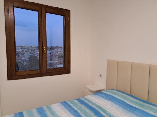 Una habitación blanca con una cama y una ventana. en Orosei Apart, en Orosei