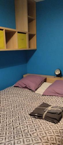 une chambre avec un lit avec un mur bleu dans l'établissement Chambres indépendantes et lumineuses, à Aleçon