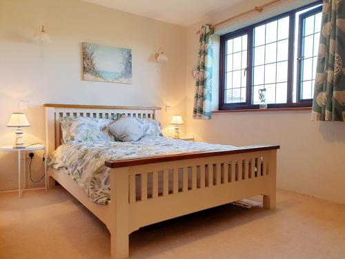 a bedroom with a wooden bed with two windows at Bay Tree Cottage - cosy home near beach in Woolacombe