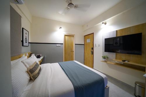 a bedroom with a bed and a flat screen tv at Olive Hotel Kundalahalli by Embassy Group in Bengaluru