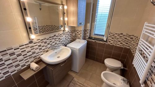 a bathroom with a sink and a toilet and a mirror at La vedetta di Castrocucco in Tortora
