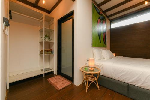a bedroom with a bed and a table with a lamp at The HIJAU Camp & Cabin in Gopeng