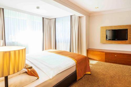 a hotel room with a bed and a flat screen tv at EUROPÄISCHER HOF Bad Gastein in Bad Gastein