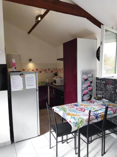 Il comprend une cuisine équipée d'une table, d'un réfrigérateur, d'une table et de chaises. dans l'établissement Gîte entre fécamp et etretat, à Mentheville