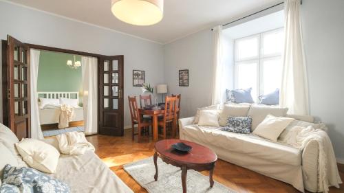 Una sala de estar con un sofá blanco y una mesa. en Vintage apartments Floriańska street - By Hosty, en Cracovia