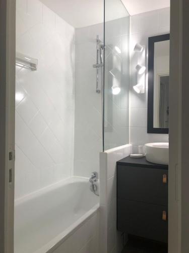 une salle de bain blanche avec une baignoire et un lavabo dans l'établissement Appt familial 5 Pers avec Piscine et Tennis, à Le Touquet-Paris-Plage