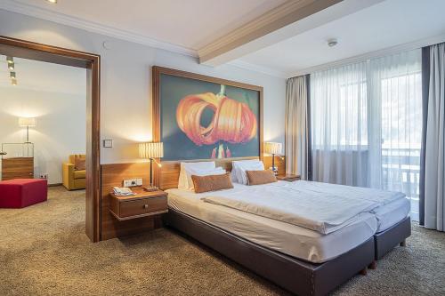 a bedroom with a large bed with a painting on the wall at EUROPÄISCHER HOF Bad Gastein in Bad Gastein