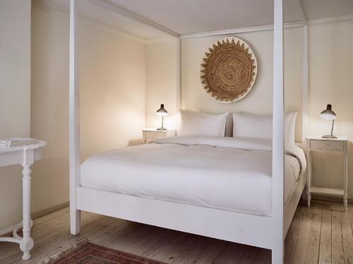 a white bedroom with a four poster bed at Grecotel Plaza Beach House in Rethymno Town