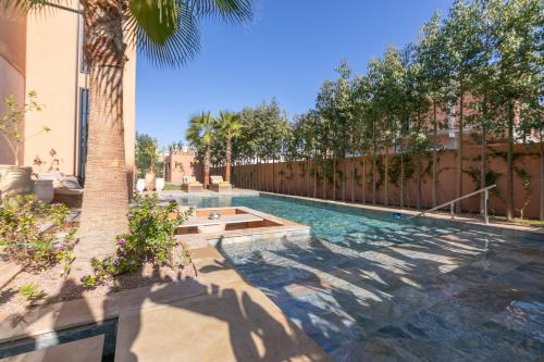 a swimming pool with a palm tree and a fence at Dar Al Ikhwa, Lodge de luxe à Marrakech in Sfiani