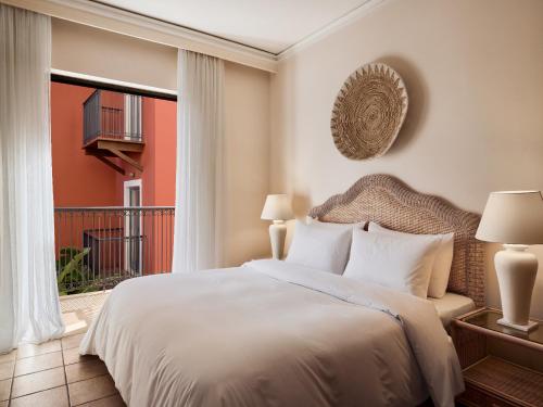 a bedroom with a large bed and a balcony at Grecotel Plaza Beach House in Rethymno Town