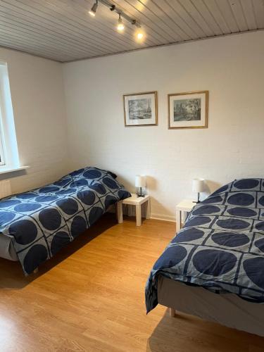 a bedroom with two beds and two tables in it at Ferielejlighed i Iller ved Ans in Ans
