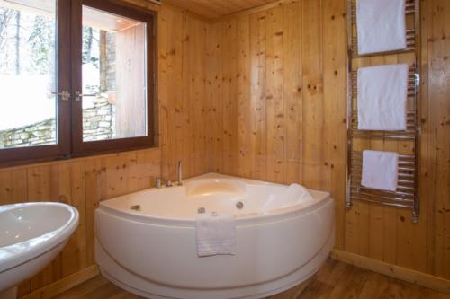 Chalet Les Arolles- Catered Chalet -Half Board في تينيِ: حمام مع حوض استحمام كبير ومغسلة