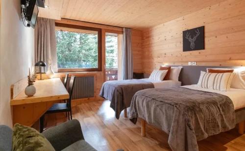 Chalet Les Arolles- Catered Chalet -Half Board في تينيِ: غرفة نوم بسريرين وطاولة ومكتب