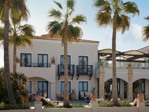 a building with palm trees in front of it at Grecotel Plaza Beach House in Rethymno Town
