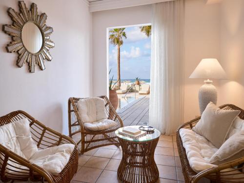 a living room with chairs and a table with a view of the ocean at Grecotel Plaza Beach House in Rethymno Town