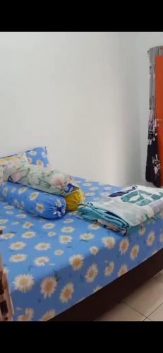 ein Bett mit einer blauen Bettdecke mit Blumen darauf in der Unterkunft Villa Brastagi Gunung Mas B7 in Berastagi