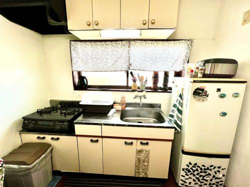 a small kitchen with a sink and a refrigerator at Shirahama in Miyazaki