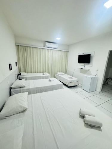 a white room with three beds and a flat screen tv at Hotel Americas in Fortaleza