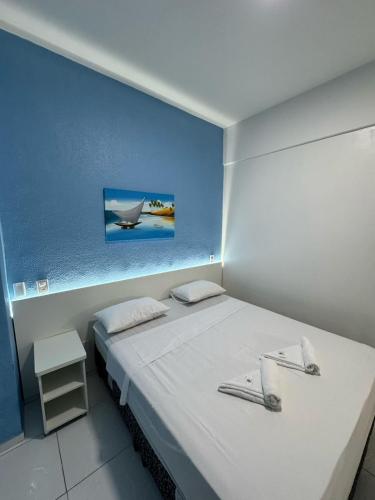 a bedroom with a white bed with a picture on the wall at Hotel Americas in Fortaleza