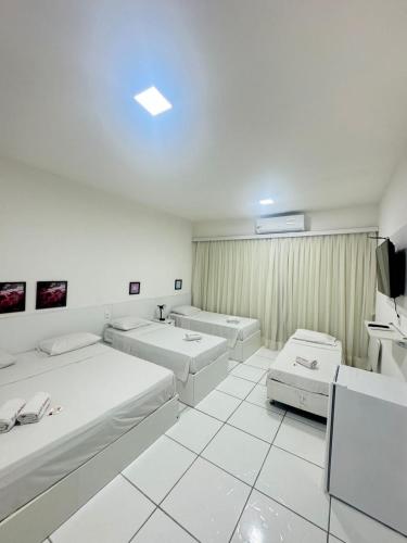 a white room with two beds and a tv at Hotel Americas in Fortaleza