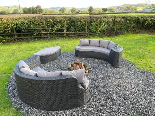 two wicker chairs and a couch sitting on gravel at The Pod at Gerycoed in Llangadog