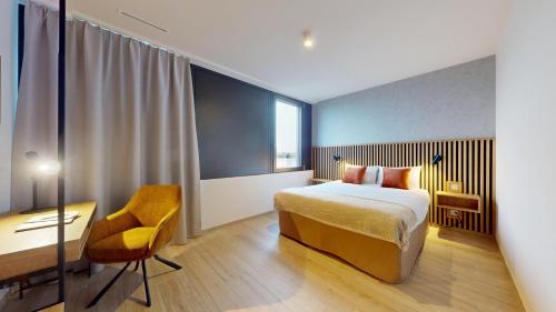 a bedroom with a bed and a desk and a chair at Nonanteneuf appart hōtel Genève Étang - Airport - contactless check-in in Geneva