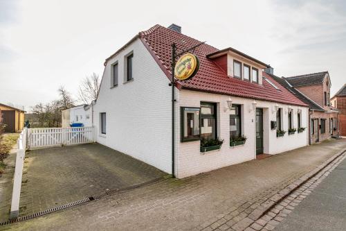a white building with a red roof on a street at Das weiße Stadthaus in Wesselburen