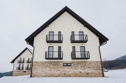 a large white house with black balconies in the snow at Apartmán BUĎA in Červená Voda