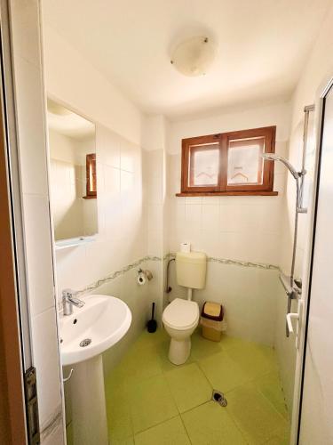 a bathroom with a white toilet and a sink at Къща за гости "Вила Релакс" in Apriltsi