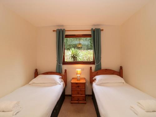 two twin beds in a room with a window at The Oak Lodge in Lyme Regis