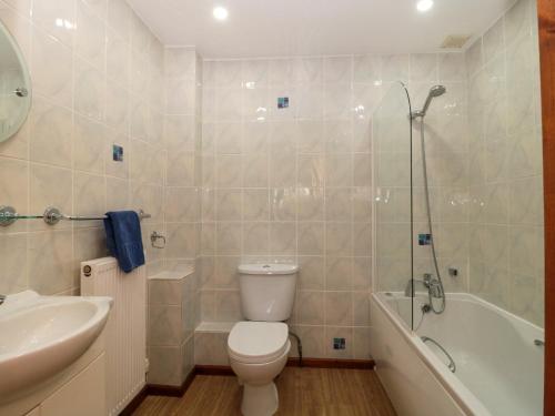 a bathroom with a toilet and a sink and a tub at The Oak Lodge in Lyme Regis