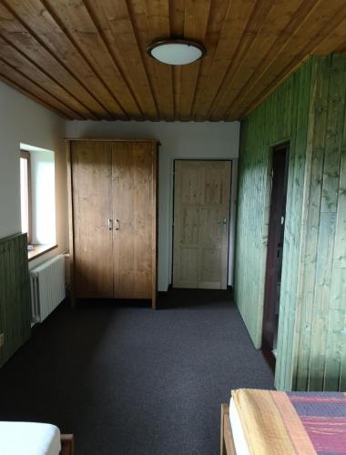 an empty room with wooden cabinets and a bed at Hájenka Nebe-apartmán NEBE in Kašperské Hory