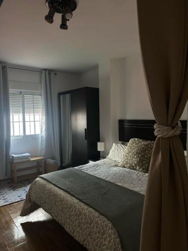 a bedroom with a large bed with a curtain at Apartamento en Huelva. in Huelva