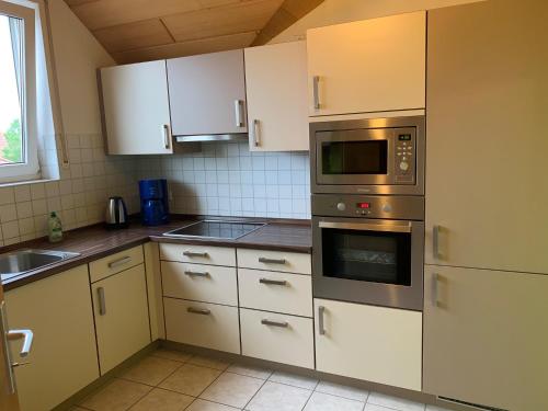 a kitchen with white cabinets and stainless steel appliances at Ferienwohnung Ortenau in Neuried