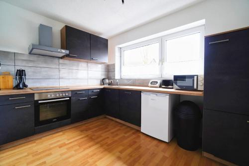 a kitchen with black cabinets and a wooden floor at Premium Apartment in Tiddische