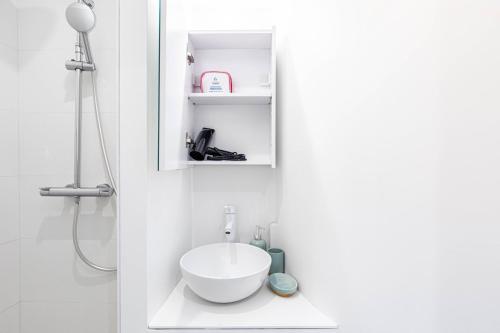 une salle de bain blanche avec un lavabo et une douche dans l'établissement GuestReady - Charming Getaway in Paris 15th, à Paris