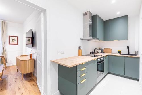 Il comprend une cuisine avec des placards verts et du parquet. dans l'établissement GuestReady - Charming Getaway in Paris 15th, à Paris