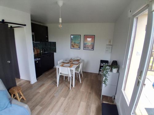 a living room with a table and a kitchen at A 300m de la plage, appartement moderne et cosy in Merville-Franceville-Plage