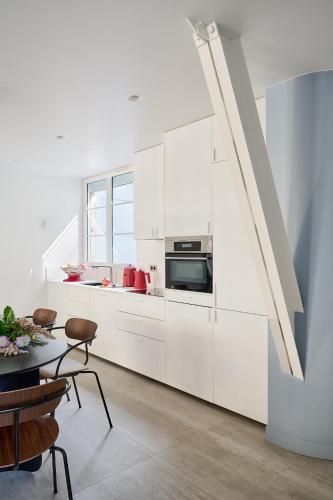 - une cuisine blanche avec des placards blancs et une table dans l'établissement Luxueux duplex en plein coeur de Paris dans le 1er arrondissement, à Paris
