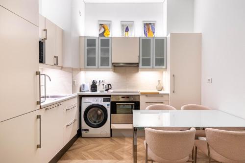une cuisine avec des armoires blanches et une table avec des chaises dans l'établissement GuestReady - Chic and central near attractions, à Paris