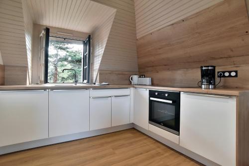 une cuisine avec des armoires blanches et une fenêtre dans l'établissement Pierre 23 - A 200m de la plage parking privé, à Fréhel